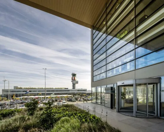 Vooraanzicht van Rotterdam The Hague Airport met de verkeerstoren en een modern kantoorgebouw op de voorgrond.